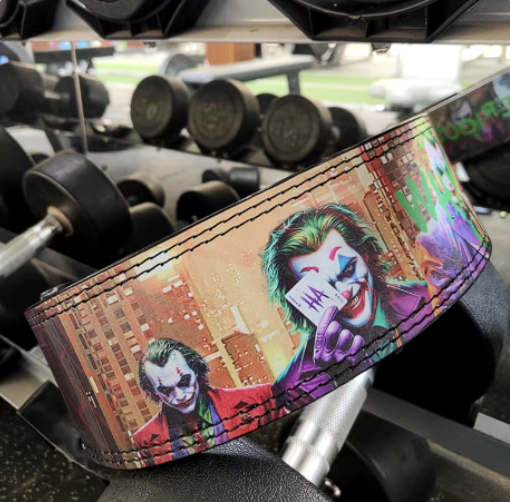 Joker Cowhide Powerlifting Belt with Joker design in gym setting, adjustable lever buckle for strength training.